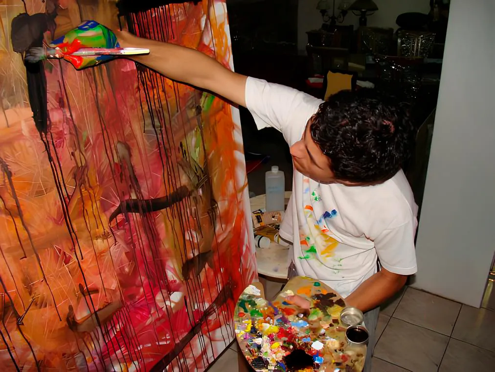 Nuno Duque de braço estendido a pintar uma tela grande, com tinta vermelha e laranja a escorrer
