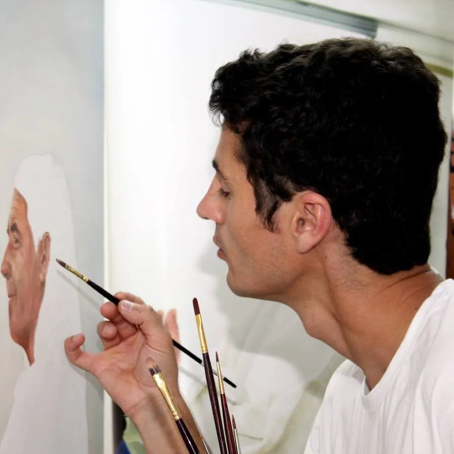 Nuno Duque a pintar um retrato de perto, com vários pincéis na mão