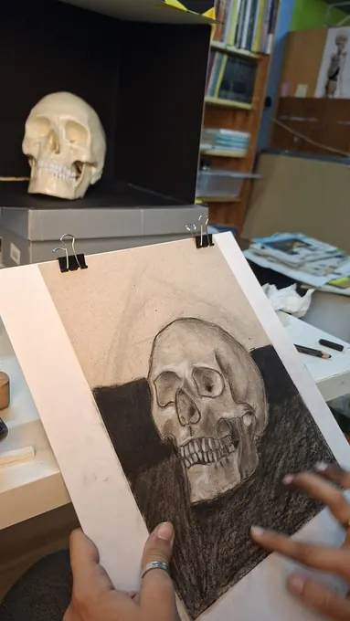 Estudo de uma caveira a carvão, com o modelo de gesso ao fundo