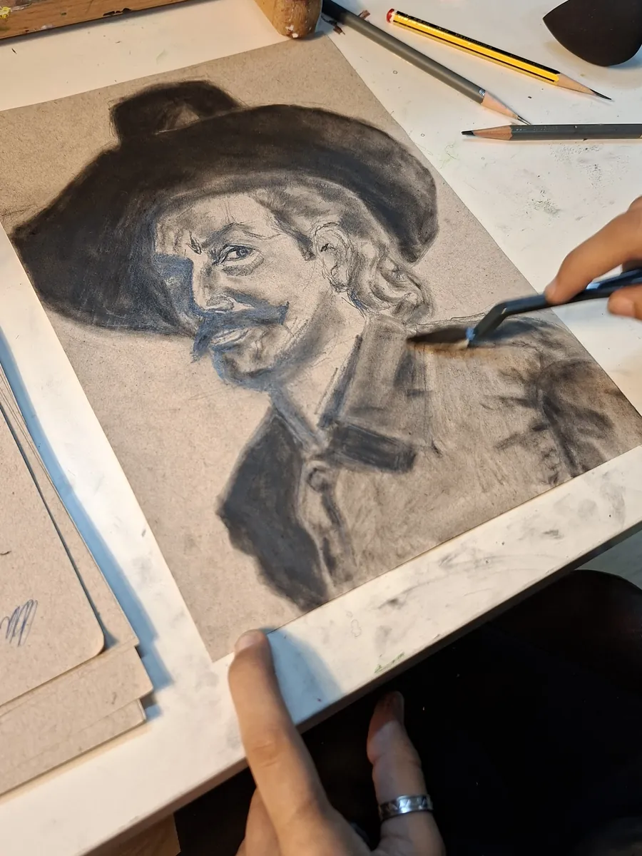 Um aluno desenha um retrato a carvão numa aula do atelier